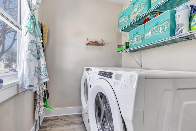 laundry area with laundry area, baseboards, wood finished floors, and washing machine and clothes dryer