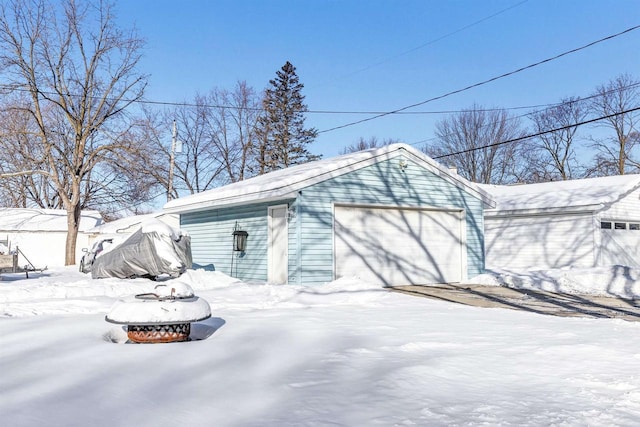 snow covered garage with a detached garage