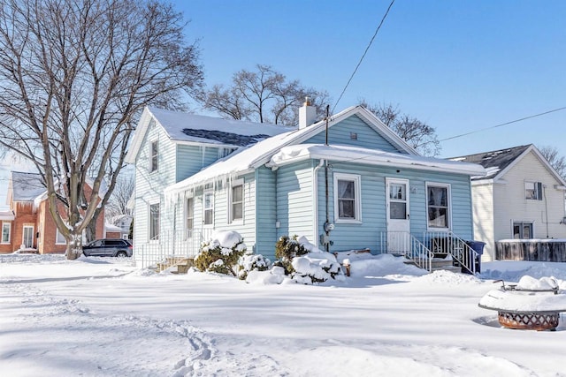 snow covered rear of property with a chimney