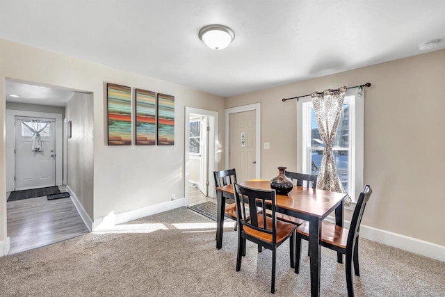 dining space featuring light colored carpet and baseboards