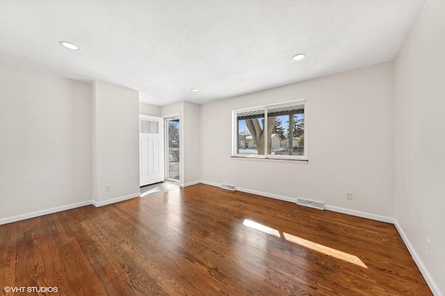 empty room featuring baseboards, visible vents, and wood finished floors