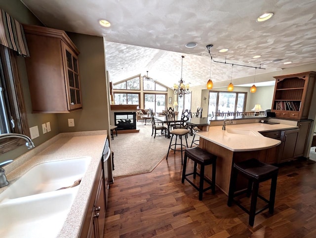 kitchen with glass insert cabinets, pendant lighting, a sink, and a kitchen breakfast bar