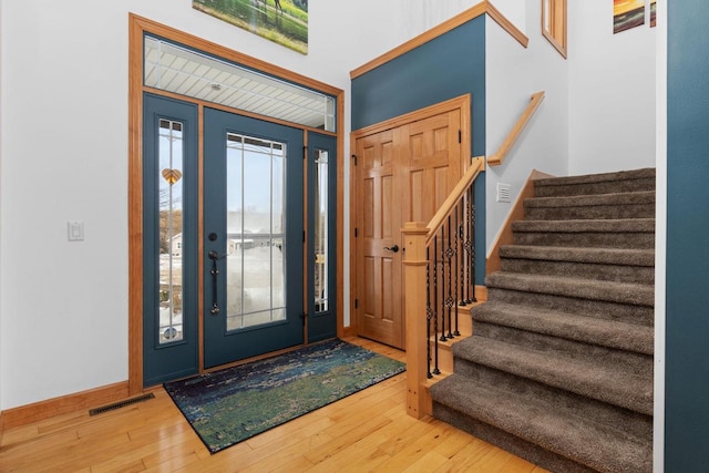 foyer featuring stairway, plenty of natural light, visible vents, and wood finished floors