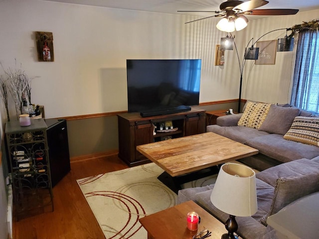 living area with dark wood-style floors, a ceiling fan, and baseboards