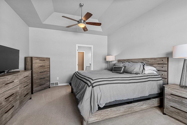 bedroom with ceiling fan, light carpet, visible vents, baseboards, and a tray ceiling