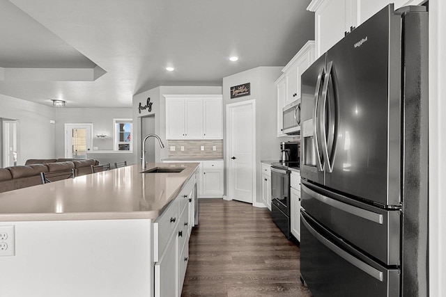 kitchen featuring appliances with stainless steel finishes, light countertops, a kitchen island with sink, and a sink