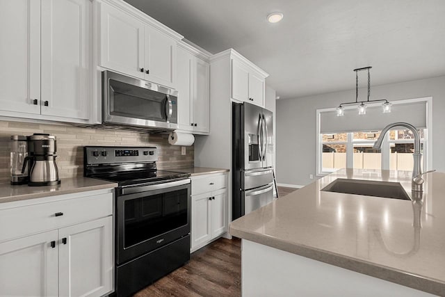 kitchen with pendant lighting, stainless steel appliances, a sink, and white cabinets