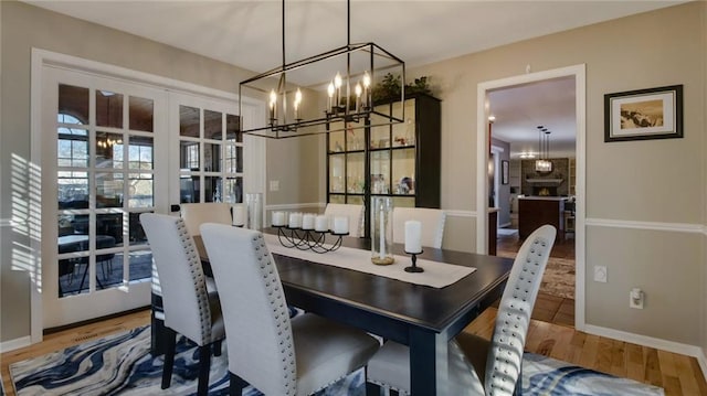 dining room featuring baseboards, a chandelier, and wood finished floors