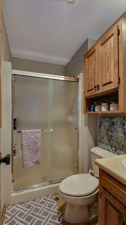 bathroom featuring toilet, a shower stall, and vanity