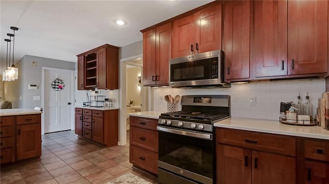 kitchen with brown cabinets, stainless steel appliances, light countertops, pendant lighting, and backsplash