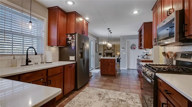 kitchen featuring a sink, light countertops, appliances with stainless steel finishes, decorative backsplash, and pendant lighting