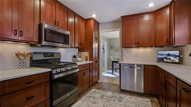 kitchen with recessed lighting, stainless steel appliances, light countertops, brown cabinets, and tasteful backsplash