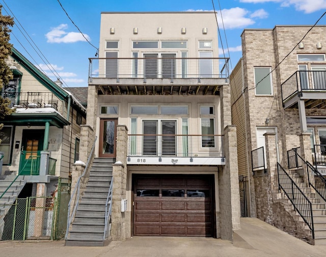 multi unit property featuring a garage, driveway, stairway, and stucco siding