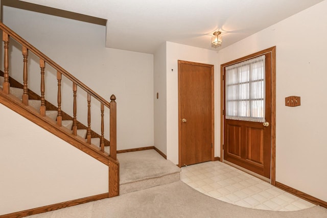 foyer featuring light floors, stairs, and baseboards