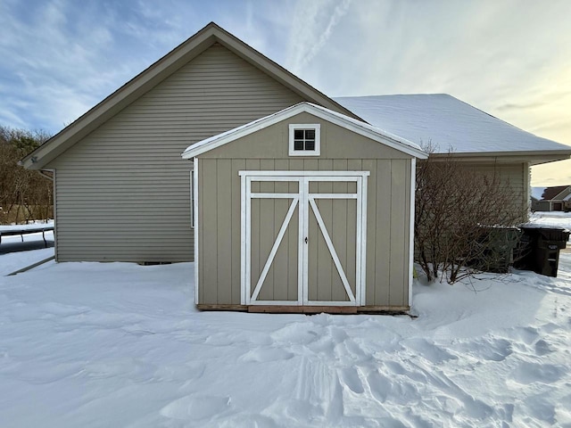 snow covered structure featuring a storage unit and an outdoor structure