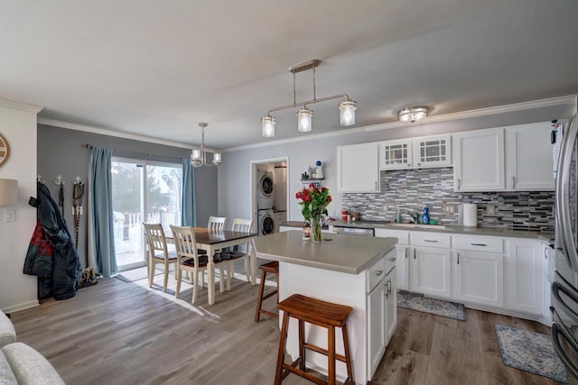 kitchen featuring glass insert cabinets, stacked washer and dryer, a center island, and white cabinets