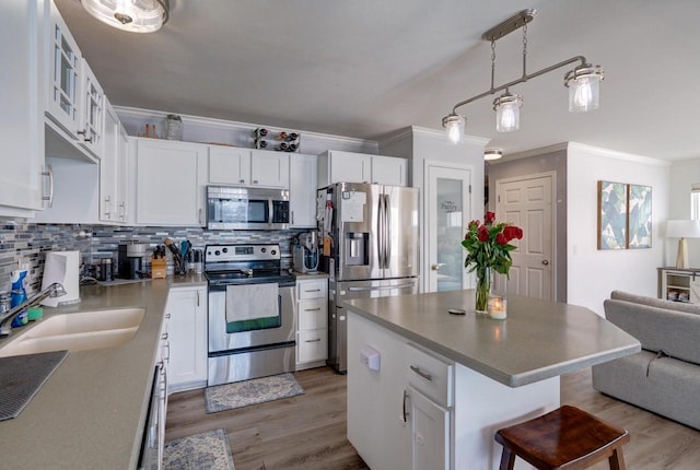 kitchen with a kitchen island, white cabinetry, stainless steel appliances, and a sink