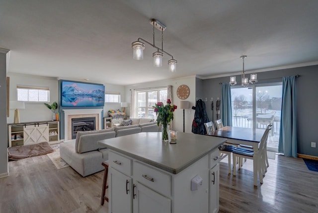 kitchen with light wood-style flooring, open floor plan, decorative light fixtures, a center island, and white cabinetry