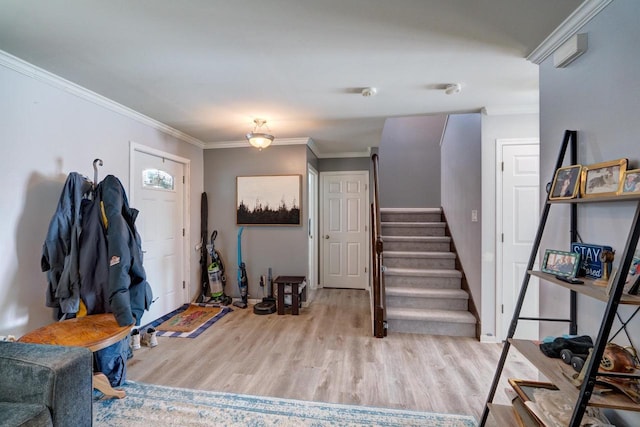 foyer with light wood-type flooring, stairs, and ornamental molding