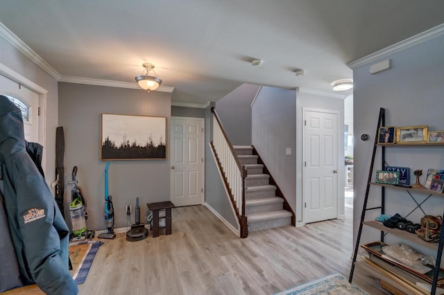 entryway with stairs, ornamental molding, light wood-style flooring, and baseboards