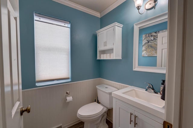 half bathroom featuring a wainscoted wall, vanity, toilet, and crown molding