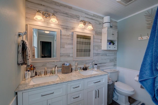 bathroom featuring crown molding, visible vents, a sink, and wainscoting