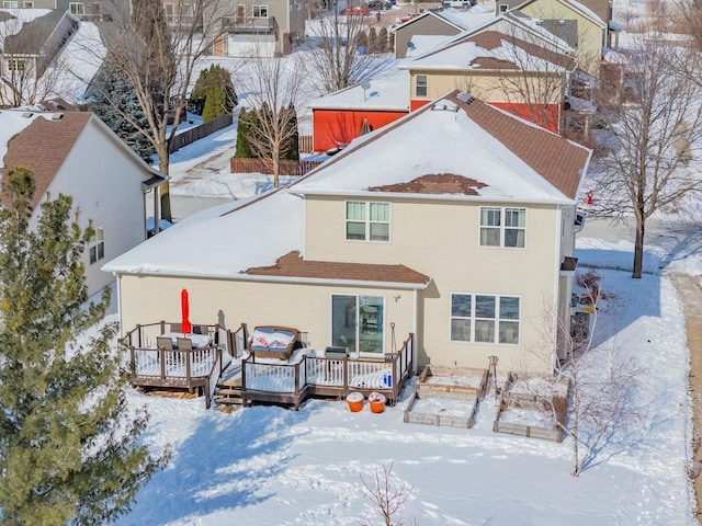 snow covered back of property with a deck