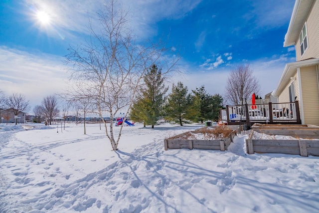 snowy yard with a vegetable garden and a deck