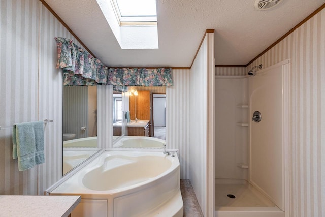 bathroom featuring a skylight, a textured ceiling, vanity, and wallpapered walls