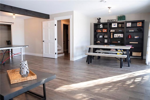 interior space featuring dark wood-style flooring, beam ceiling, and baseboards