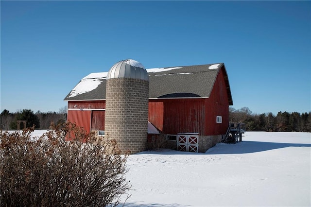 view of snow covered exterior featuring an outbuilding, a barn, and a garage