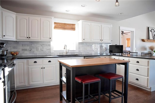 kitchen featuring dark wood-type flooring, white cabinets, a sink, and wood counters