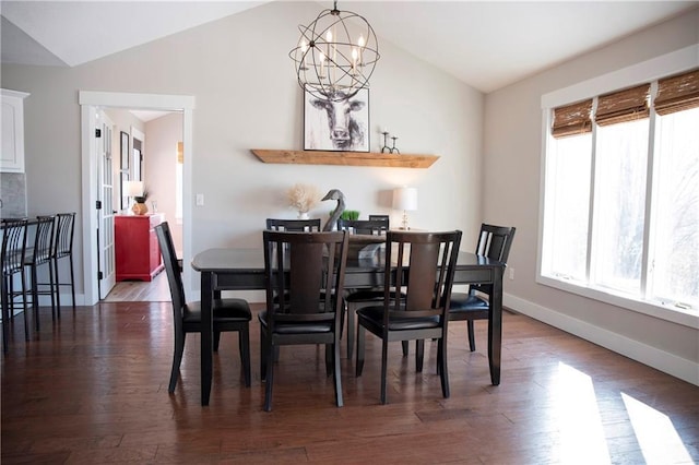 dining room featuring lofted ceiling, dark wood-type flooring, an inviting chandelier, and a healthy amount of sunlight