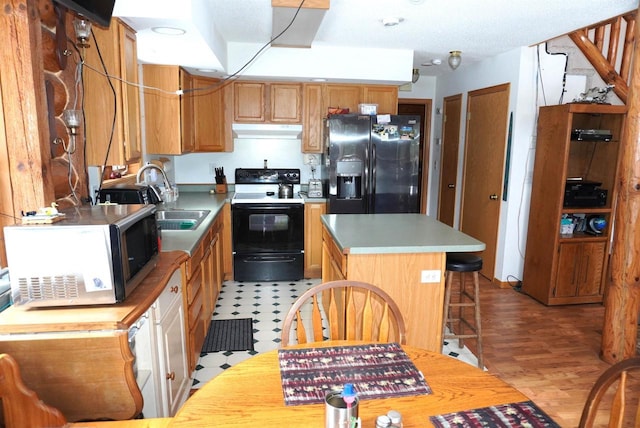 kitchen with electric stove, stainless steel microwave, a kitchen island, fridge with ice dispenser, and under cabinet range hood