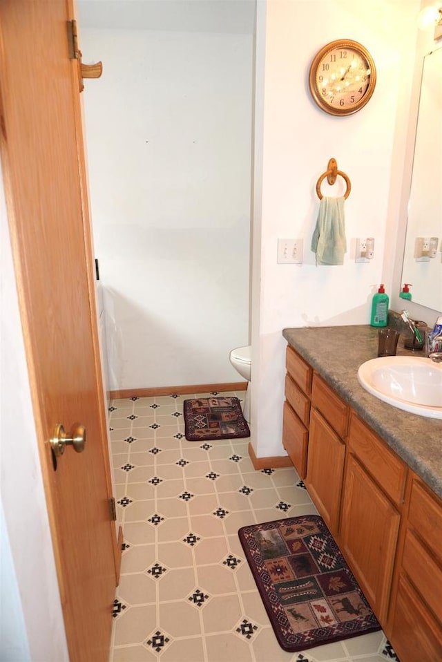 bathroom featuring baseboards, vanity, and toilet