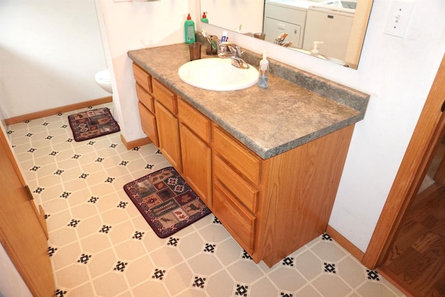 half bathroom with toilet, baseboards, vanity, and tile patterned floors