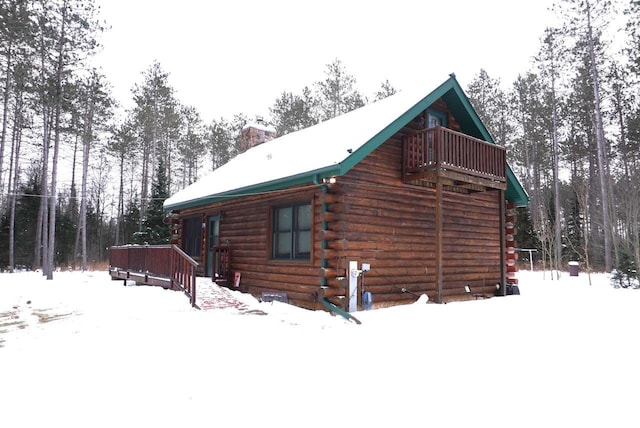 snow covered property featuring a chimney and log exterior