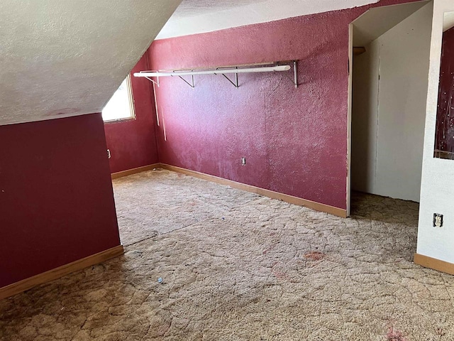 bonus room with carpet, lofted ceiling, a textured wall, a textured ceiling, and baseboards