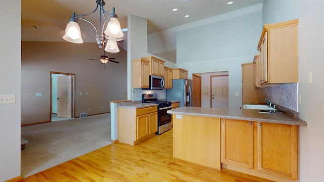 kitchen featuring stainless steel appliances, light brown cabinetry, a peninsula, and light countertops