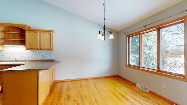 unfurnished dining area featuring lofted ceiling, visible vents, light wood-style floors, a sink, and baseboards