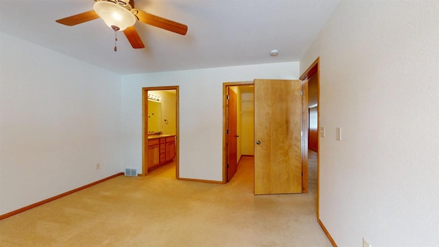 unfurnished bedroom featuring baseboards, visible vents, light colored carpet, ceiling fan, and ensuite bathroom