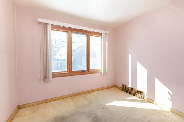 spare room with baseboards and light colored carpet