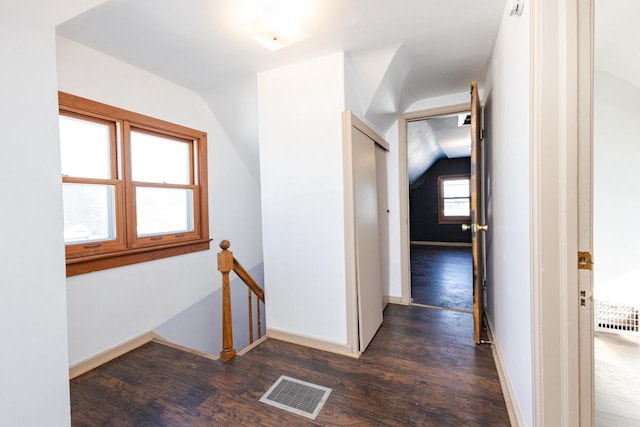 hall featuring lofted ceiling, dark wood-type flooring, an upstairs landing, and visible vents