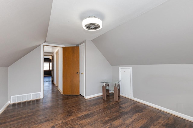 additional living space with lofted ceiling, dark wood-style flooring, visible vents, and baseboards