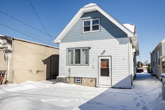 snow covered property featuring central AC and fence