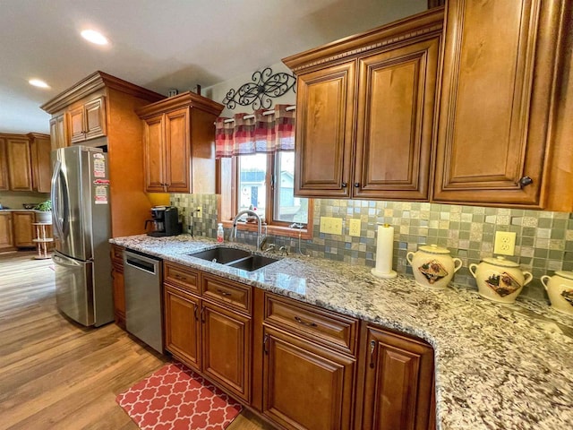 kitchen with decorative backsplash, brown cabinets, stainless steel appliances, light wood-type flooring, and a sink