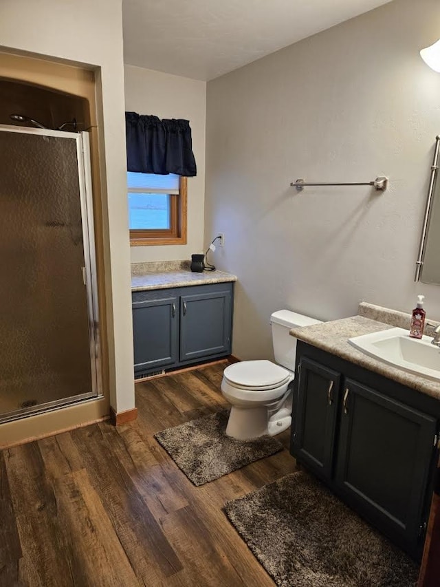 bathroom with toilet, a stall shower, wood finished floors, and vanity