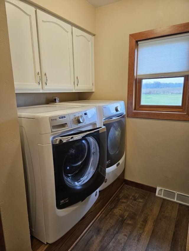 washroom with washing machine and clothes dryer, visible vents, cabinet space, dark wood-type flooring, and baseboards