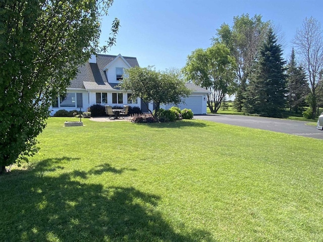 cape cod home featuring an attached garage, driveway, and a front yard