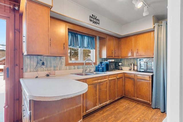 kitchen with brown cabinets, light countertops, a sink, and light wood finished floors